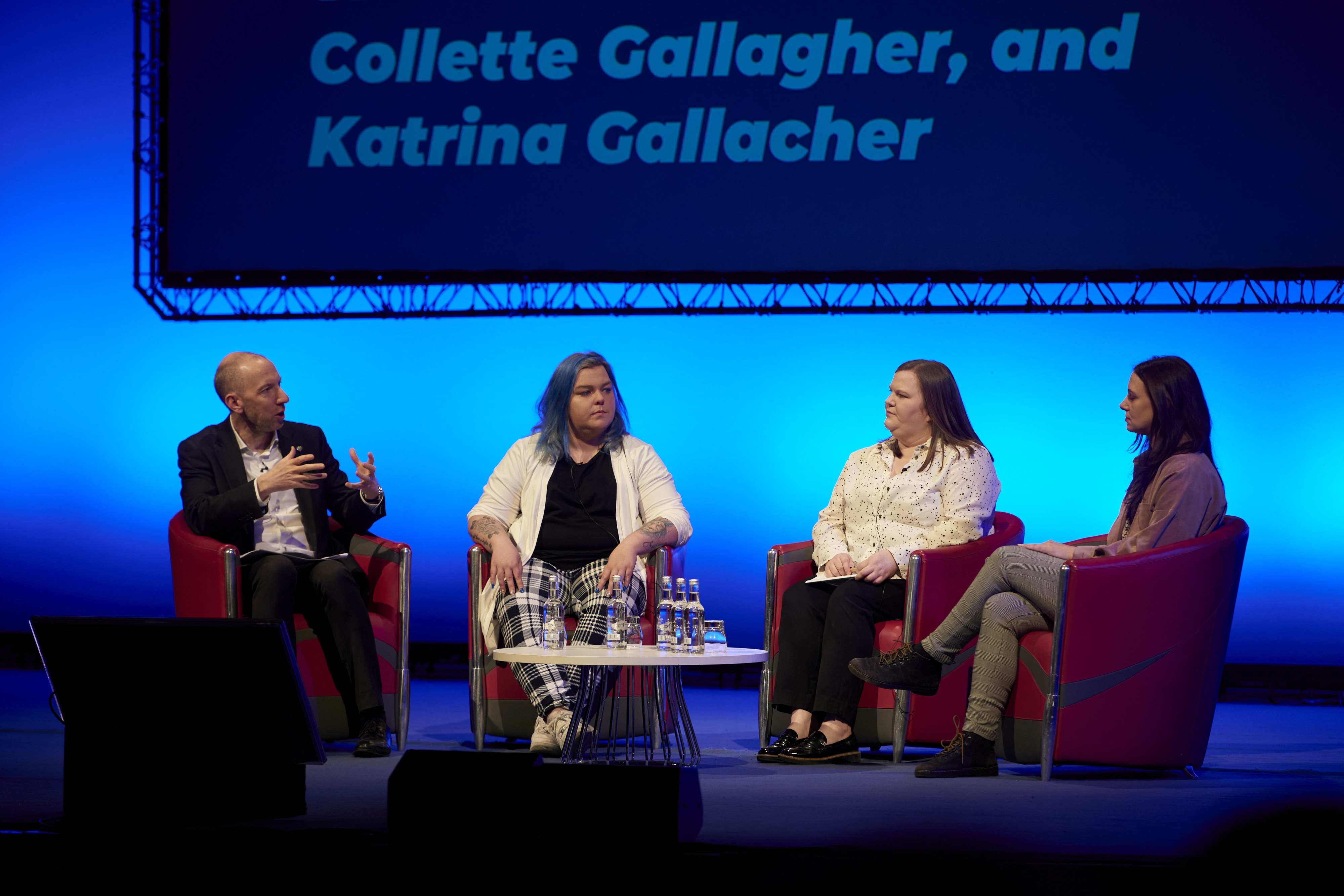 The panel talking to each other on the conference stage.